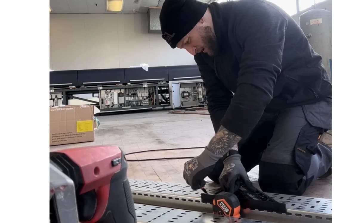 Technician performs electrical work on equipment in an industrial training facility classroom.